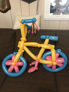 an inflatable bicycle is sitting on the couch with balloons attached to it's seat