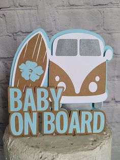 a wooden sign that says baby on board next to a brick wall with a van and surfboard