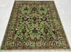 a green rug with an intricate design on the top and bottom is laying on a white floor