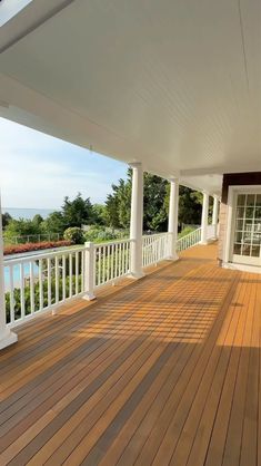 a wooden deck with white railing and pillars