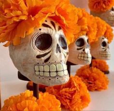 three skulls with orange flowers on their heads