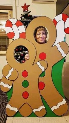 a woman standing in front of a cardboard cutout of a gingerbread man