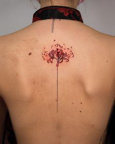 the back of a woman's neck with a flower tattoo on it