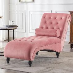 a pink chaise lounge chair sitting on top of a rug