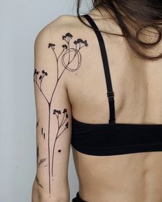 the back of a woman's shoulder with flowers tattooed on her left arm and chest