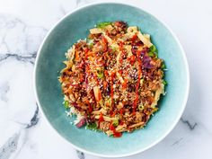 a blue bowl filled with food on top of a white countertop next to a marble table