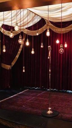 a stage with red curtains and lights hanging from the ceiling