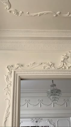 an ornate white frame with chandelier hanging from the ceiling