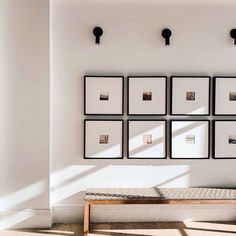 a white room with pictures hanging on the wall and a bench in front of it