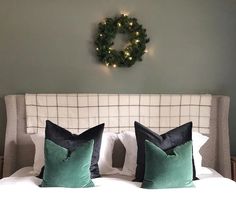 a bed with two green pillows and a wreath on the wall above it's headboard