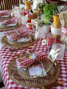 the table is set with red and white checkered cloths, plates, silverware, utensils, and napkins