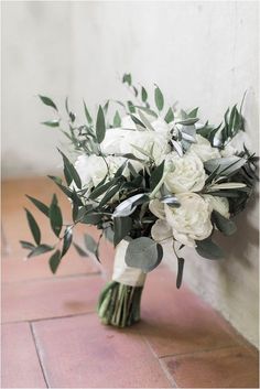 a bouquet of white flowers sitting on top of a tiled floor next to a wall