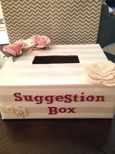 a white box that says suggestion box with flowers on the top and an open lid