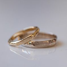 two gold wedding rings with fingerprints on them sitting on a white table top