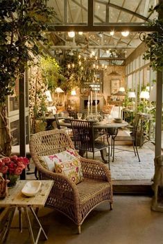 a patio with wicker furniture and potted plants on the table, surrounded by greenery