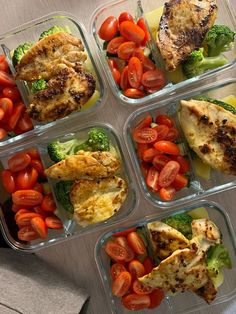 four plastic containers filled with chicken, tomatoes and broccoli on top of a table