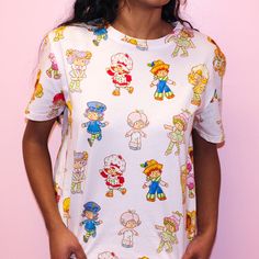 Strawberry Shortcake and Friends AOP T-Shirt - Cakeworthy Playful Character Print T-shirt With Relaxed Fit, Playful Short Sleeve T-shirt With All Over Print, Playful Unisex T-shirt With Character Print, Playful Short Sleeve Top For Fan Merchandise, Cute Cartoon Print T-shirt, Kawaii Crew Neck Tops For Fan Merchandise, Kawaii Fan Merchandise Tops With Crew Neck, Kawaii Cartoon Print T-shirt With Relaxed Fit, Kawaii Style Fan Merchandise Tops With Crew Neck