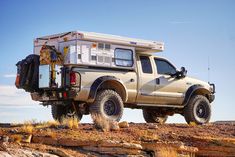 a truck with a camper attached to it's bed is parked in the desert