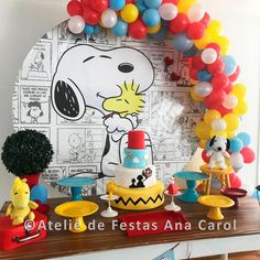 a table topped with balloons and cake next to a cartoon character balloon arch on top of a wall