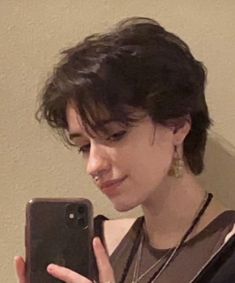 White person with a medium short dark brown haircut holding their phone up to a mirror. They are wearing a brown tank top and black zip up hoodie. They are wearing 2 necklaces, earrings and a septum piercing. Women With Really Short Hair, Short Wavy Hair Gender Neutral, Androgyny Haircut, French Bob Mullet, Masc Pfp Drawing, Very Short Feminine Haircut, Tomboy With Short Hair, Short Hairstyles Masculine, Short Masculine Haircuts For Women Straight Hair