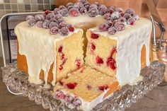 a cake with white frosting and raspberries is on a glass platter