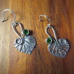 This is a cute elven design leaf and genuine Diopside set of earrings. The leaves are hammer textured in the brutalist style, but the design is elven. The leaf is an Aspen leaf with a stem that has become a tendril. The tendril catches the ear hook then comes back down to the shoulder of the leaf, ending in a graceful spiral. These are botanically correct aspen leaves. The stones are very nice, AAA grade, 4mm round, green Chrome Diopside. Add the great outdoors to your day with these handsome ea Green Leaf-shaped Sterling Silver Earrings, Hand Forged Green Earrings For Gift, Elven Design, Earrings Long Silver, Aspen Leaves, Aspen Leaf, Long Silver Earrings, Botanical Earrings, Green Chrome