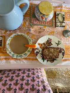 a table topped with plates and cups filled with food next to a teapot on top of a table