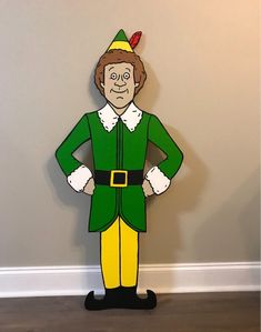 a cardboard cutout of an elf with his hands on his hips standing in front of a wall