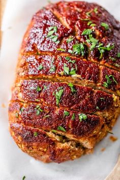 meatloaf with sauce and parsley on top sitting on parchment paper next to bread