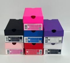 four boxes are stacked next to each other on a white surface, one is pink and the other is blue