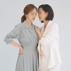 two women standing next to each other with their hands on their hipss and looking at each other