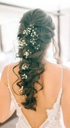 the back of a woman's head with flowers in her hair, wearing a wedding dress