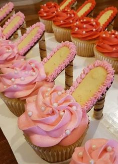 cupcakes with pink and orange frosting are arranged on a table