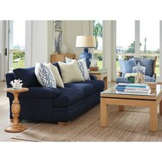 a living room with blue couches and coffee table in front of large windows overlooking the ocean