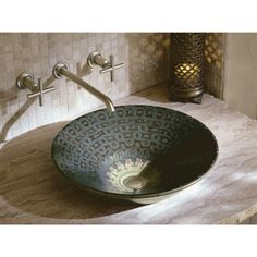 a bowl shaped sink sitting on top of a counter next to a wall mounted faucet