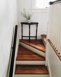 there is a plant sitting on the top of some stairs next to a small table