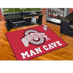 a hockey mat that says man cave on it in front of a tv and other sports equipment