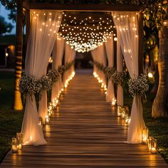 an outdoor wedding ceremony with candles and draping on the aisle, decorated with flowers and greenery