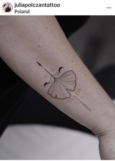 a person with a tattoo on their arm holding onto a white object in the shape of a ging sprout