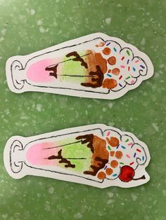 two stickers that are sitting on a green surface with some type of ice cream