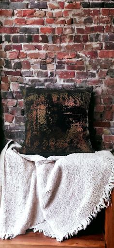 a bed with a blanket on top of it and a brick wall in the background