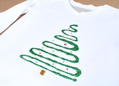 a white shirt with a green christmas tree on it