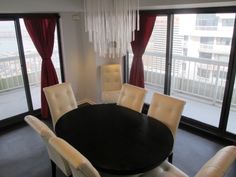 a dining room table with white chairs and red drapes on the windowsills