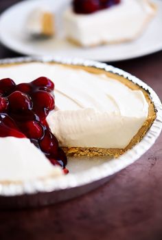 a piece of cheesecake with cherries on top is sitting on a paper plate