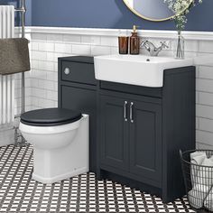 a white toilet sitting next to a black and white sink in a bathroom under a mirror