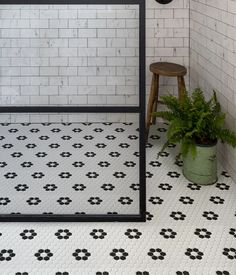 a black and white tiled bathroom with a potted plant on the floor next to it