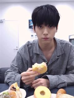 a young man sitting at a table with two plates of food in front of him