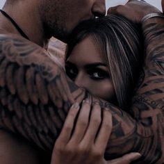 a man and woman hugging each other with tattoos on their arms