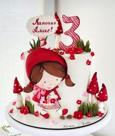 a white cake with red decorations and a girl holding a basket on top of it