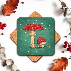 a coaster with two mushrooms on it surrounded by leaves and berries